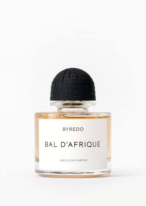 A bottle of Byredo Bal D'Afrique absolute perfume, featuring a clear glass bottle with amber-colored liquid, a white label with black text, and a textured black cap, set against a plain white background.