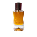 A clear glass perfume bottle filled with amber-colored liquid, featuring a faceted geometric design and a dark brown cap. The brand name 'PRISMA' is embossed on the front of the bottle.